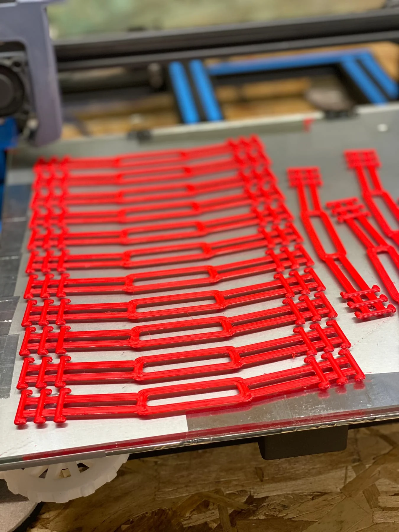 Red face-shield components arranged across a printer bed